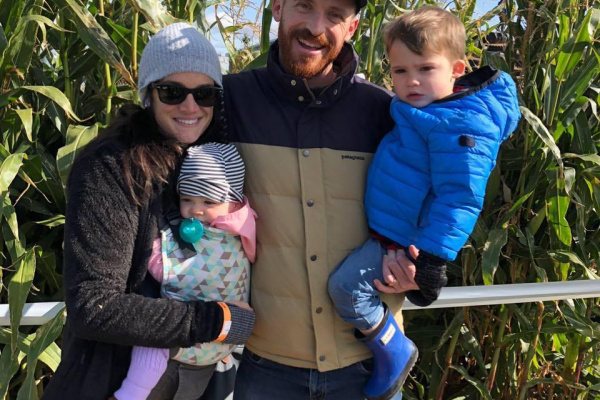 Harnish Family bundled up from cold smiling in front of corn field during the fall season.