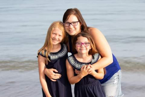 Maggie McCulley and her two daughters posing on the beach